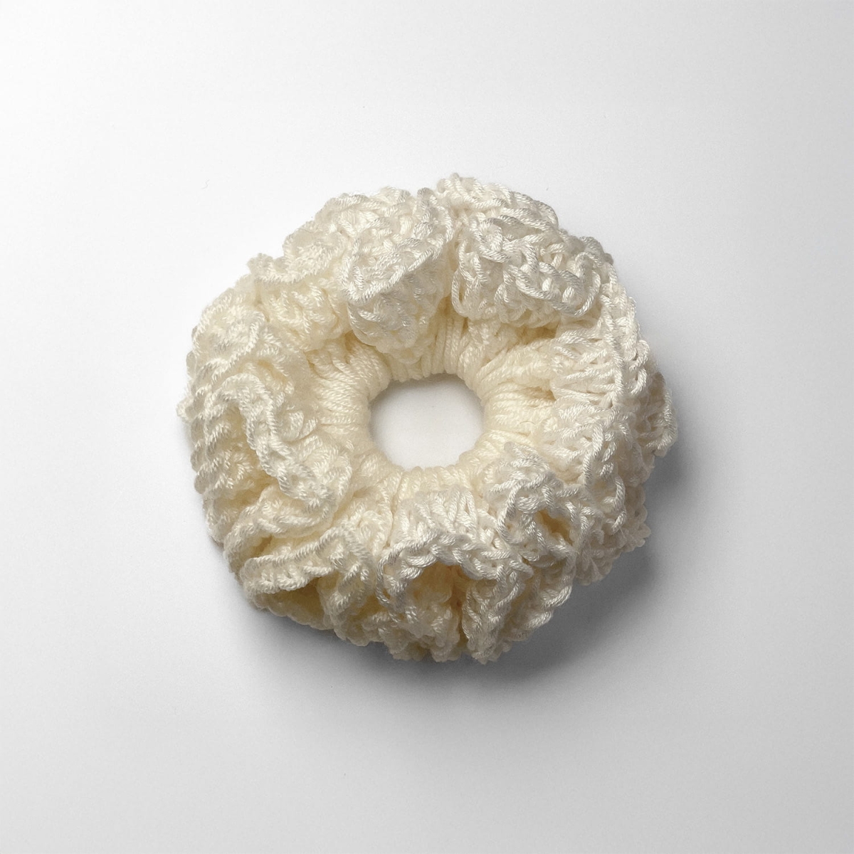 Ręcznie robiona gumka do włosów na szydełku wykonana z materiałów z upcyklingu, widok z góry na białym tle.