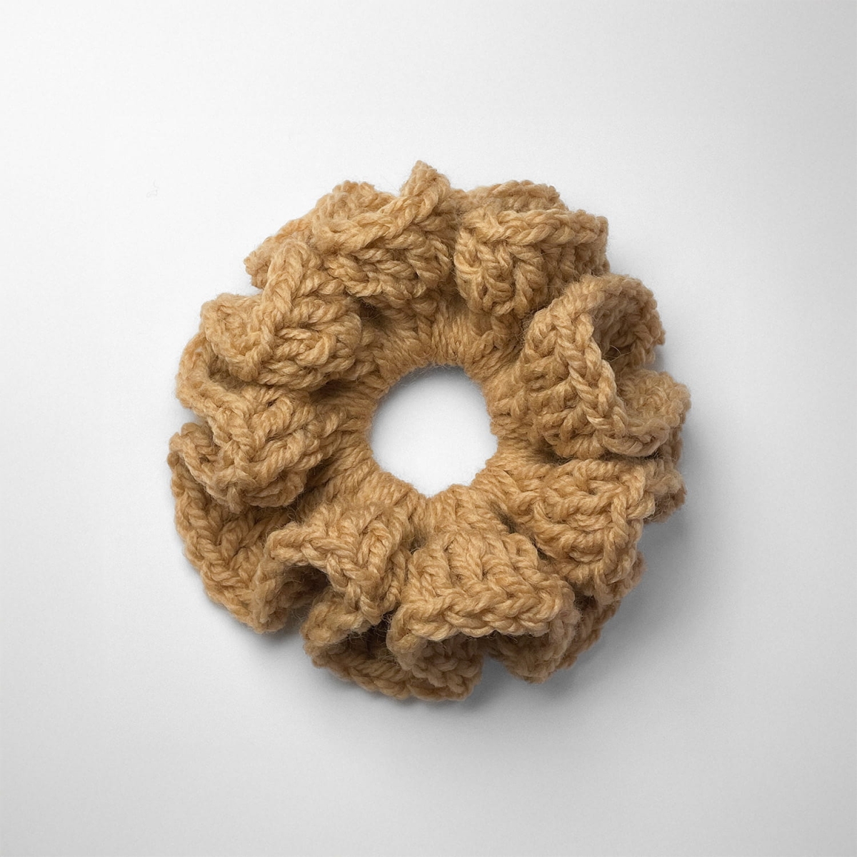 Ręcznie robiona gumka do włosów na szydełku wykonana z materiałów z upcyklingu, widok z góry na białym tle.