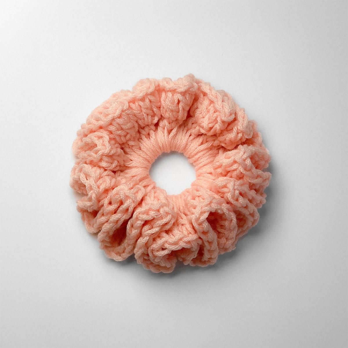 Ręcznie robiona gumka do włosów na szydełku wykonana z materiałów z upcyklingu, widok z góry na białym tle.