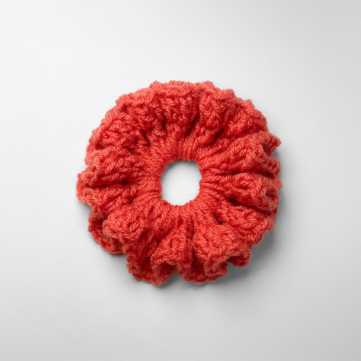 Ręcznie robiona gumka do włosów na szydełku wykonana z materiałów z upcyklingu, widok z góry na białym tle.