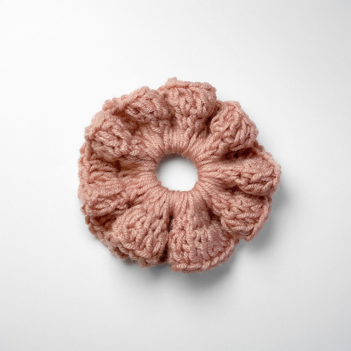 Ręcznie robiona gumka do włosów na szydełku wykonana z materiałów z upcyklingu, widok z góry na białym tle.