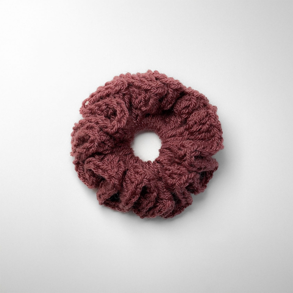 Ręcznie robiona gumka do włosów na szydełku wykonana z materiałów z upcyklingu, widok z góry na białym tle.