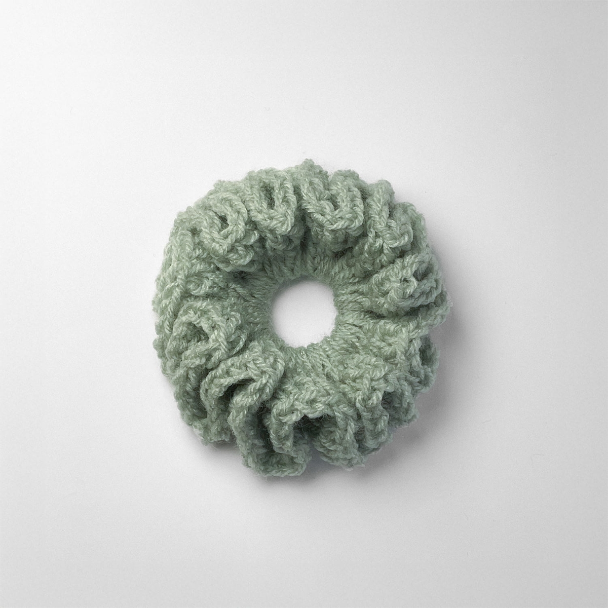 Ręcznie robiona gumka do włosów na szydełku wykonana z materiałów z upcyklingu, widok z góry na białym tle.