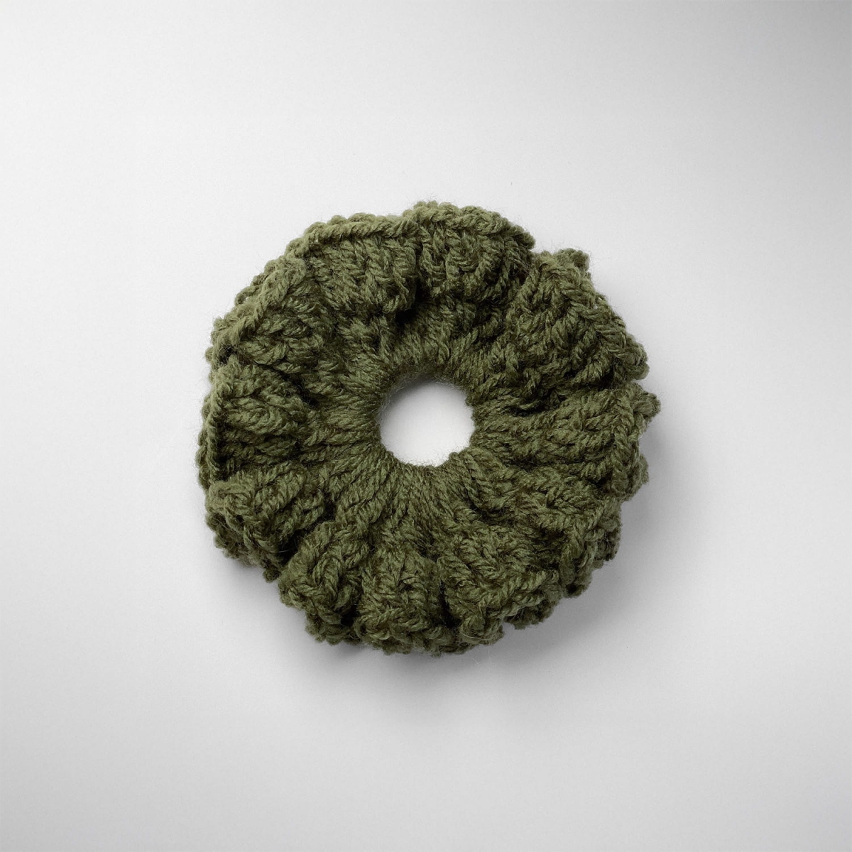 Ręcznie robiona gumka do włosów na szydełku wykonana z materiałów z upcyklingu, widok z góry na białym tle.