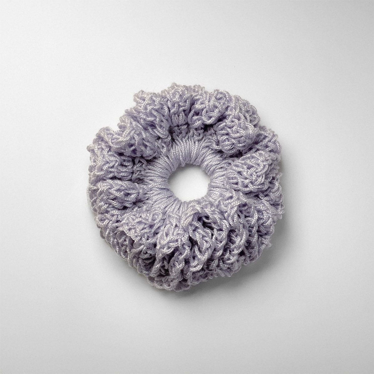 Ręcznie robiona gumka do włosów na szydełku wykonana z materiałów z upcyklingu, widok z góry na białym tle.