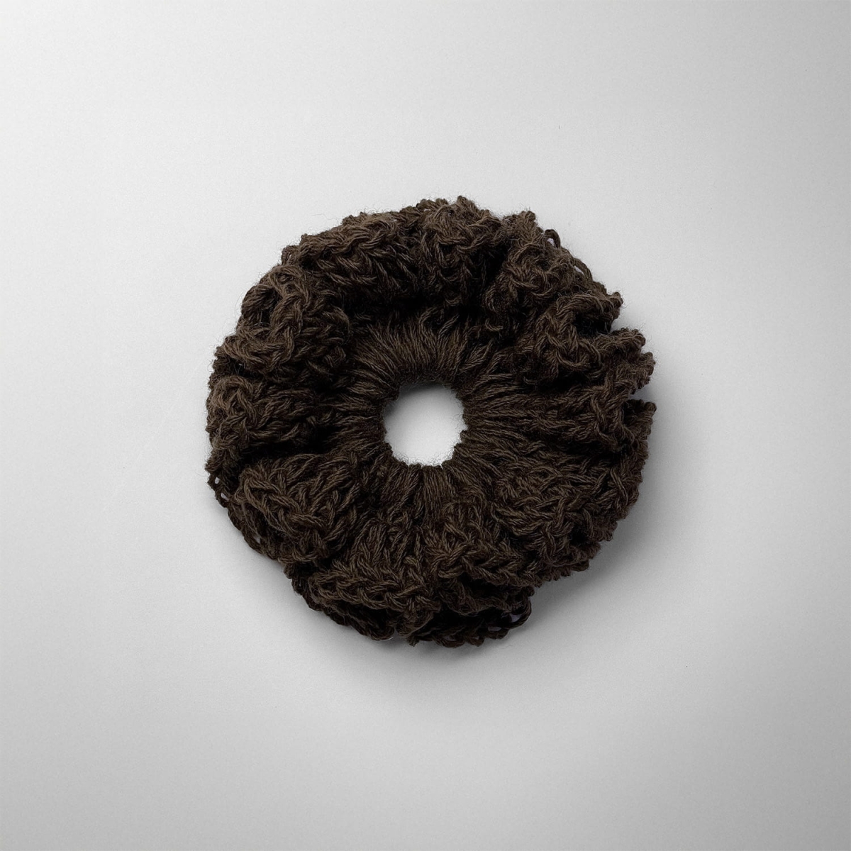 Ręcznie robiona gumka do włosów na szydełku wykonana z materiałów z upcyklingu, widok z góry na białym tle.