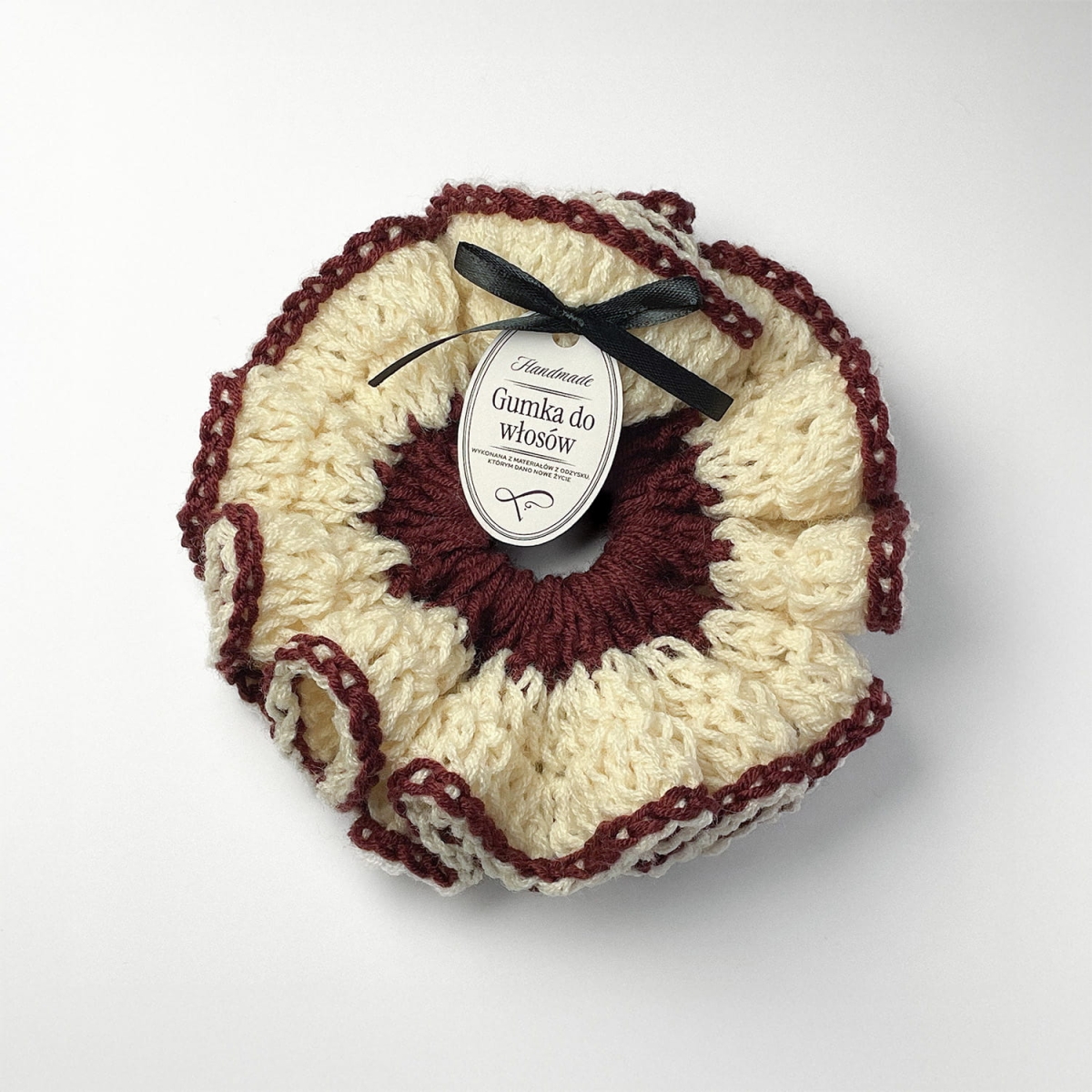 Ręcznie robiona gumka do włosów na szydełku wykonana z materiałów z upcyklingu, widok z góry na białym tle.