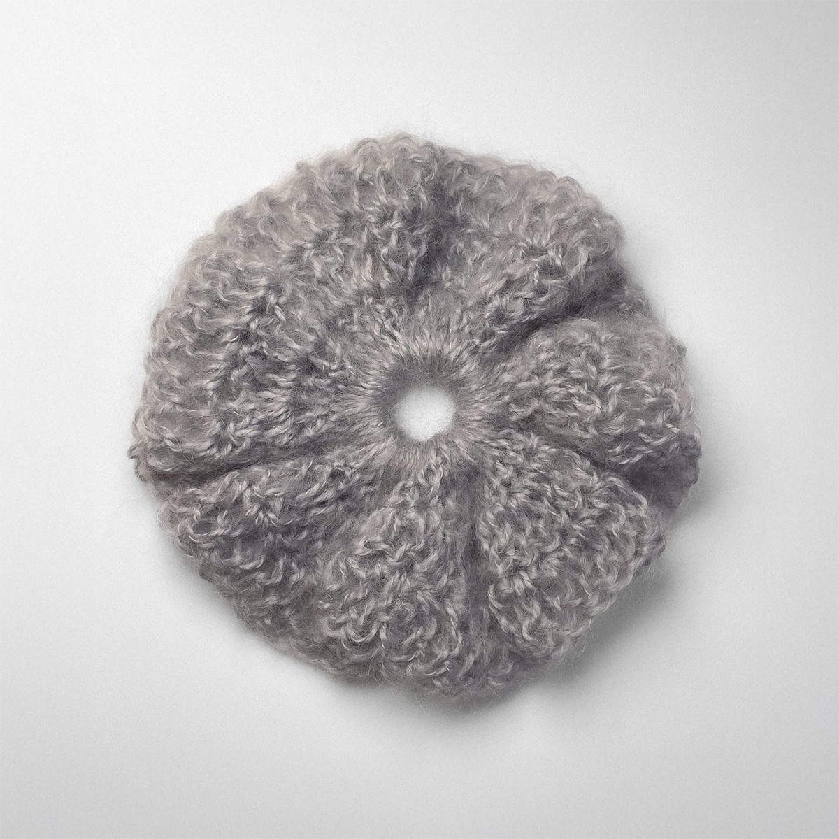 Ręcznie robiona gumka do włosów na szydełku wykonana z materiałów z upcyklingu, widok z góry na białym tle.