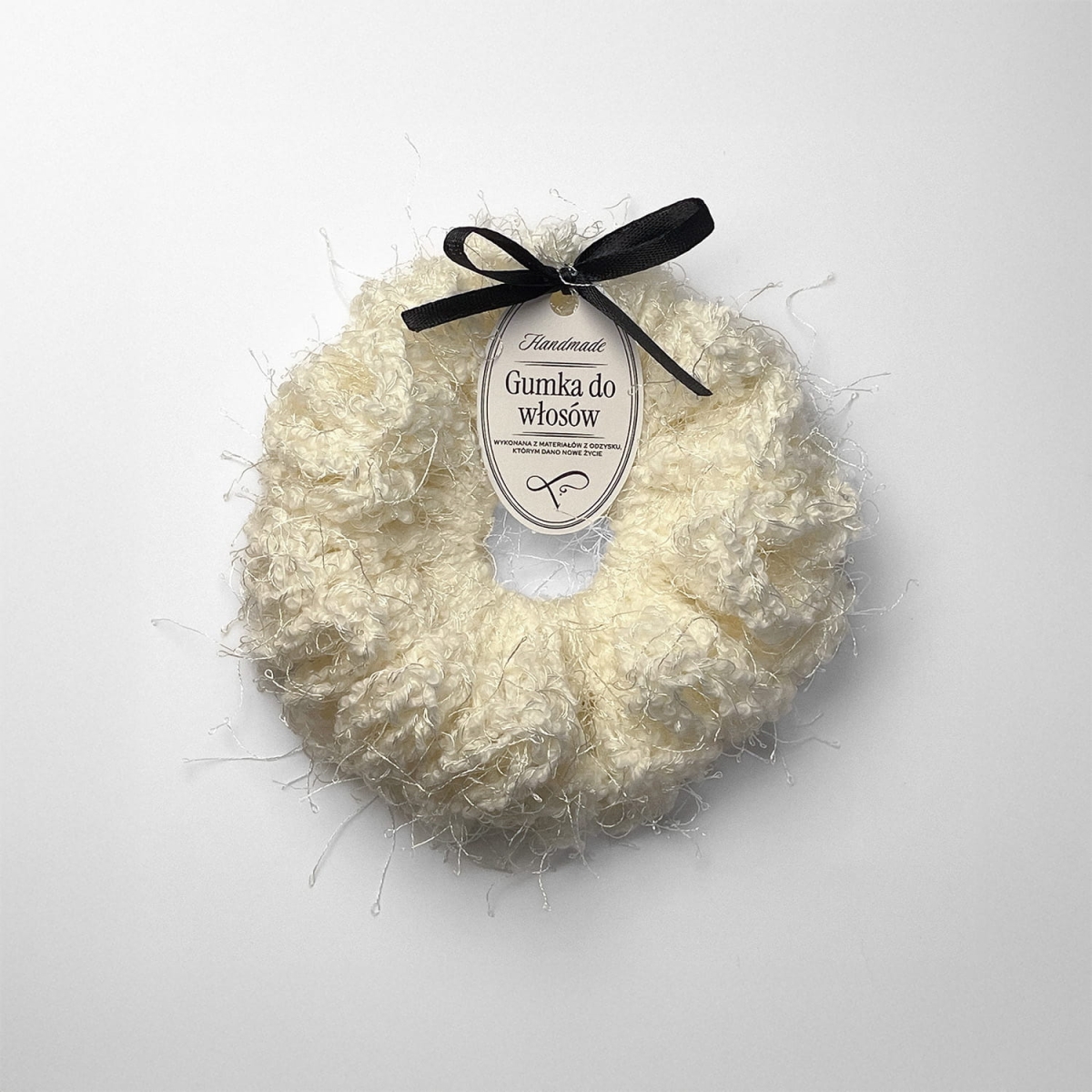 Ręcznie robiona gumka do włosów na szydełku wykonana z materiałów z upcyklingu, widok z góry na białym tle.