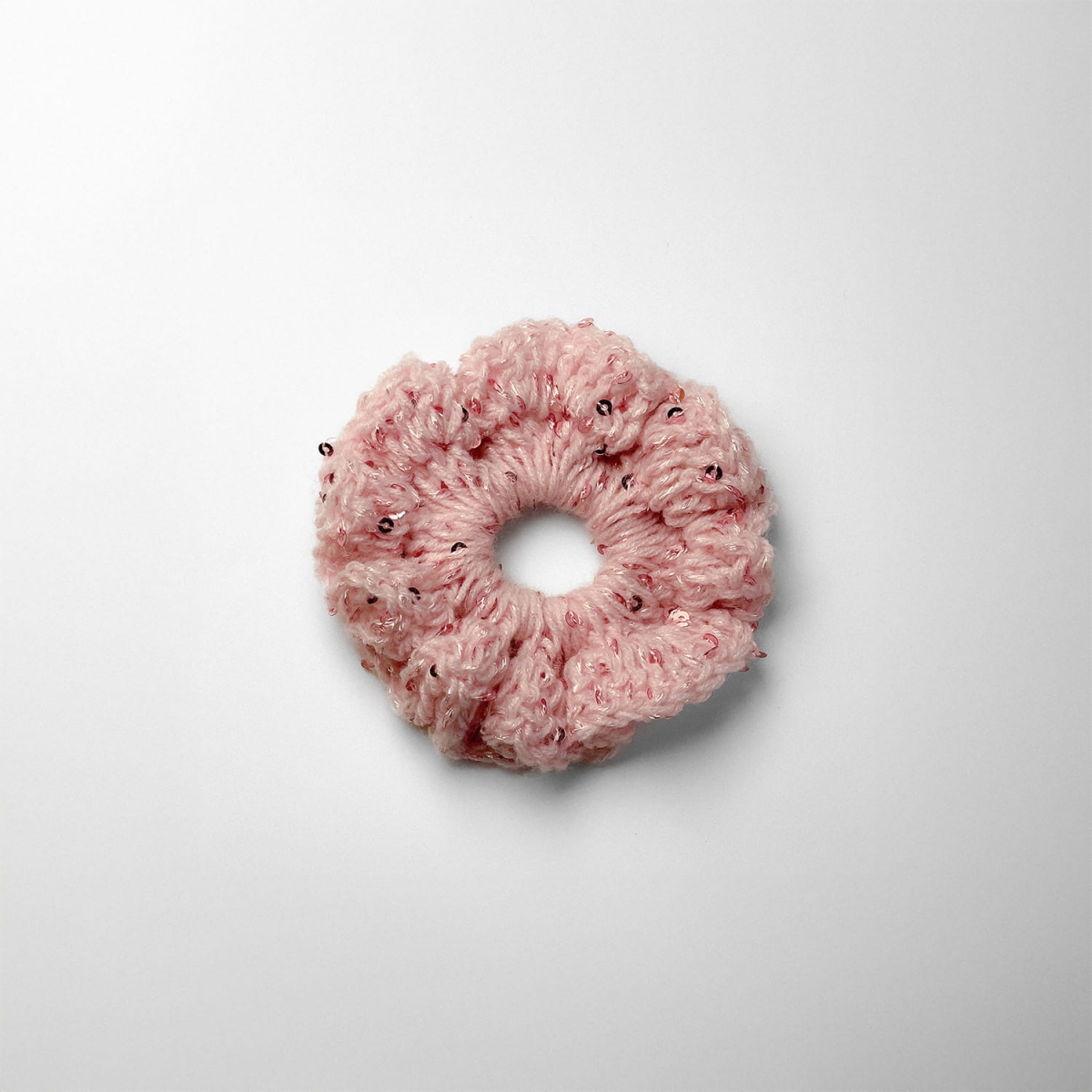 Ręcznie robiona gumka do włosów na szydełku wykonana z materiałów z upcyklingu, widok z góry na białym tle.