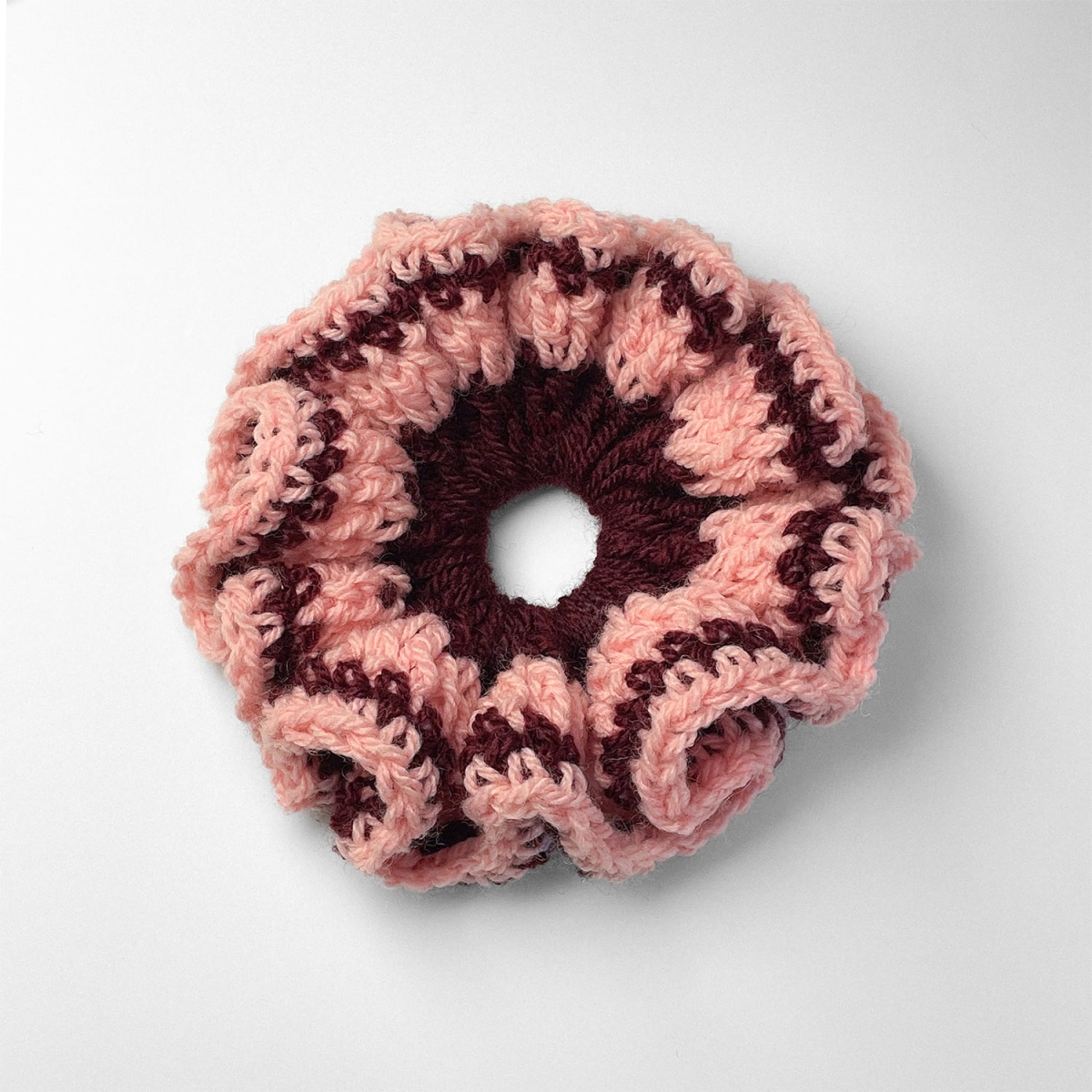 Ręcznie robiona gumka do włosów na szydełku wykonana z materiałów z upcyklingu, widok z góry na białym tle.