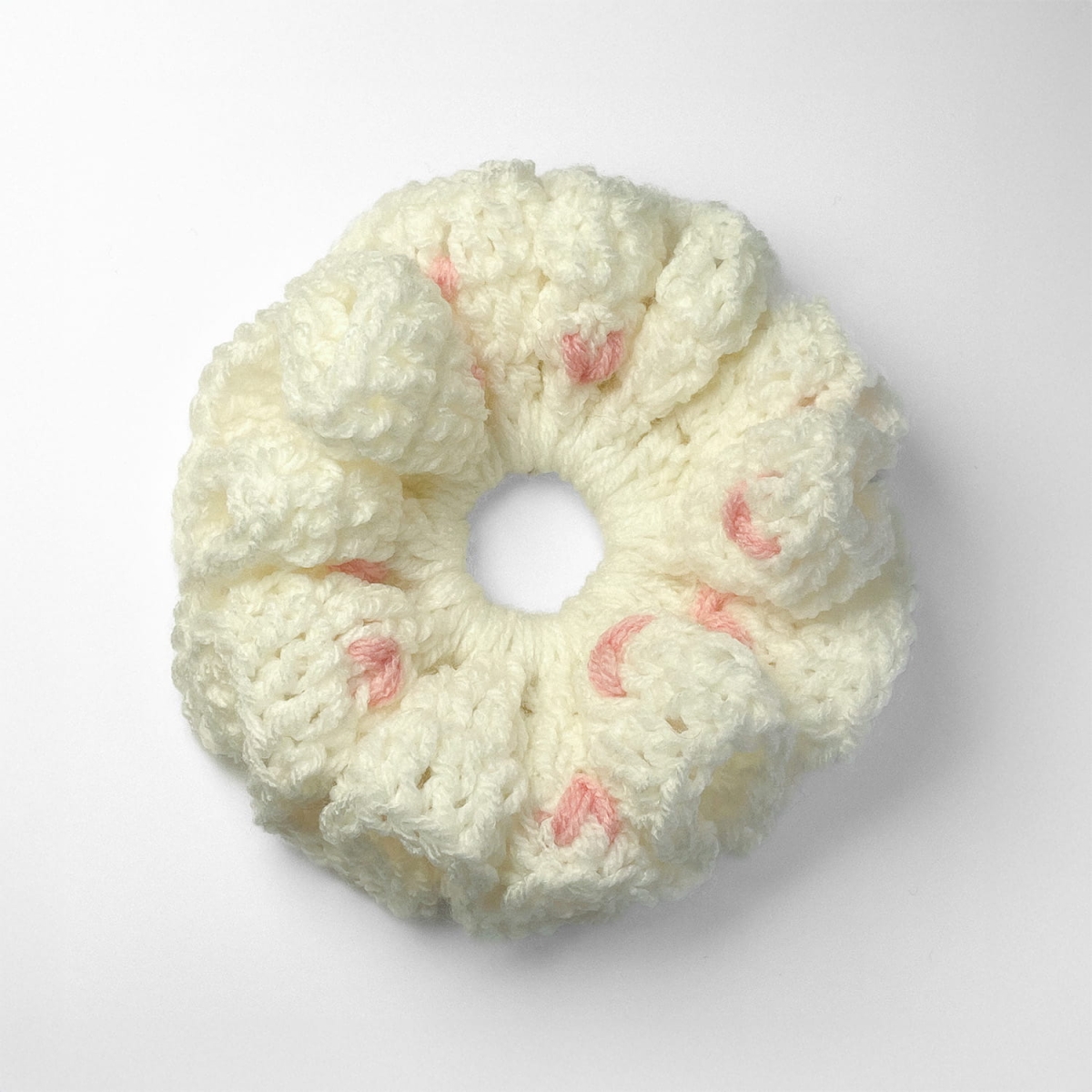 Ręcznie robiona gumka do włosów na szydełku wykonana z materiałów z upcyklingu, widok z góry na białym tle.