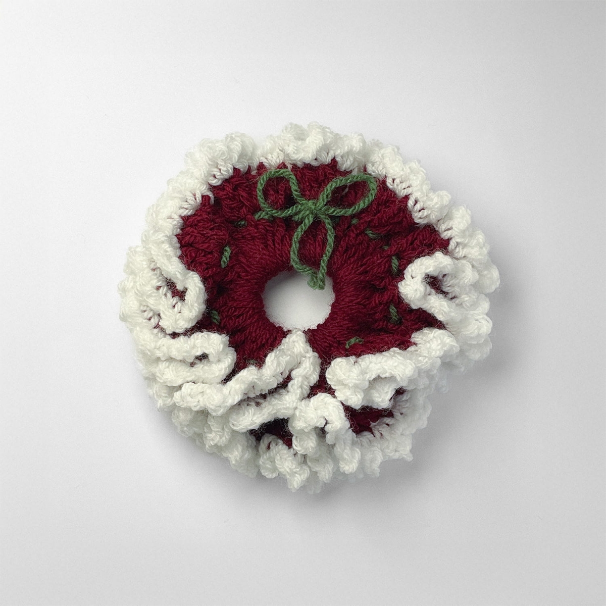 Ręcznie robiona gumka do włosów na szydełku wykonana z materiałów z upcyklingu, widok z góry na białym tle.