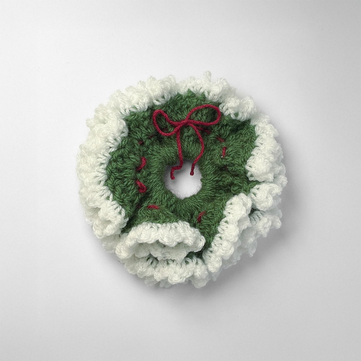 Ręcznie robiona gumka do włosów na szydełku wykonana z materiałów z upcyklingu, widok z góry na białym tle.