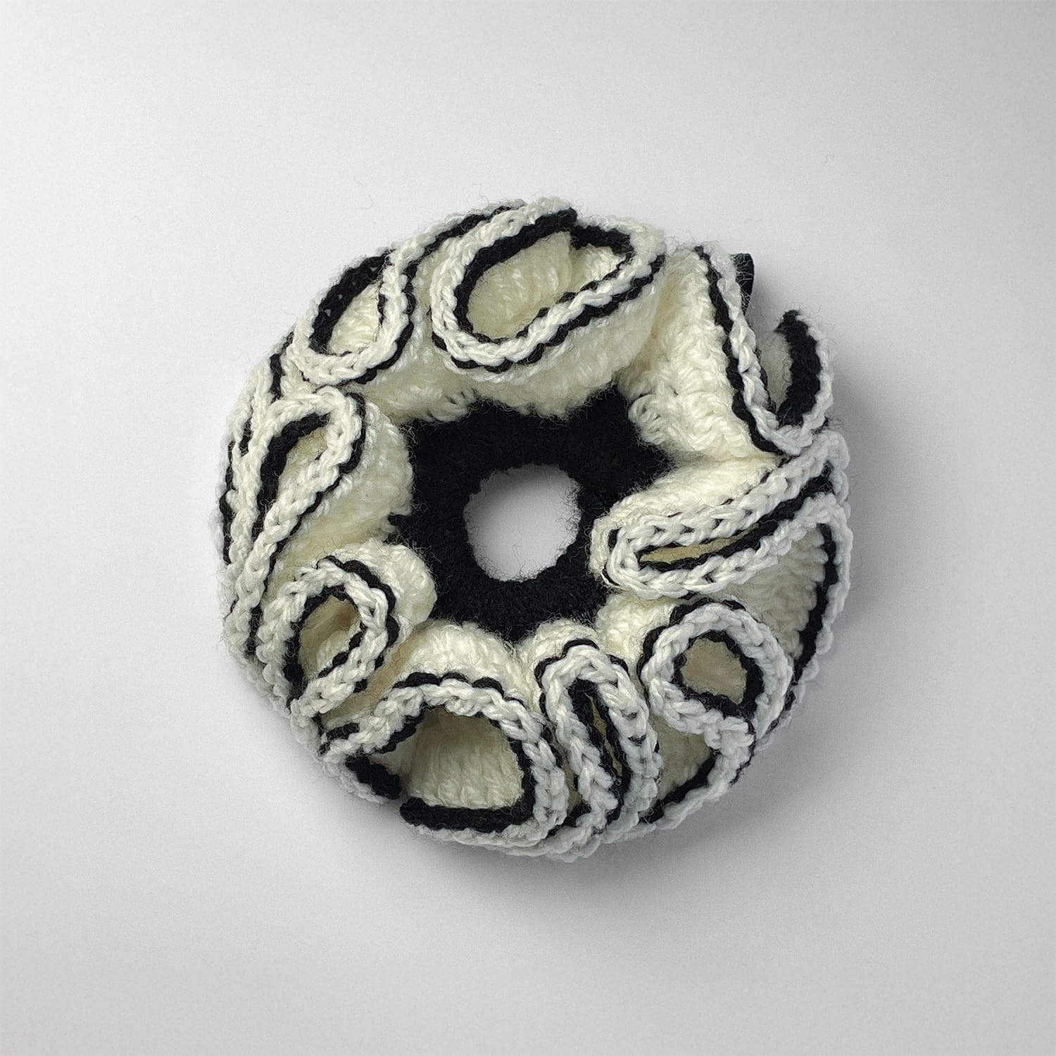 Ręcznie robiona gumka do włosów na szydełku wykonana z materiałów z upcyklingu, widok z góry na białym tle.