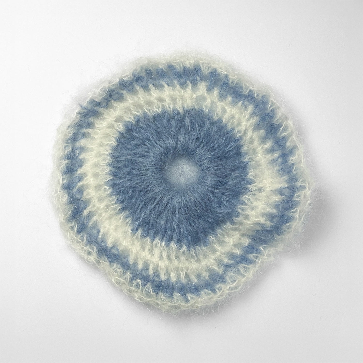 Ręcznie robiona gumka do włosów na szydełku wykonana z materiałów z upcyklingu, widok z góry na białym tle.