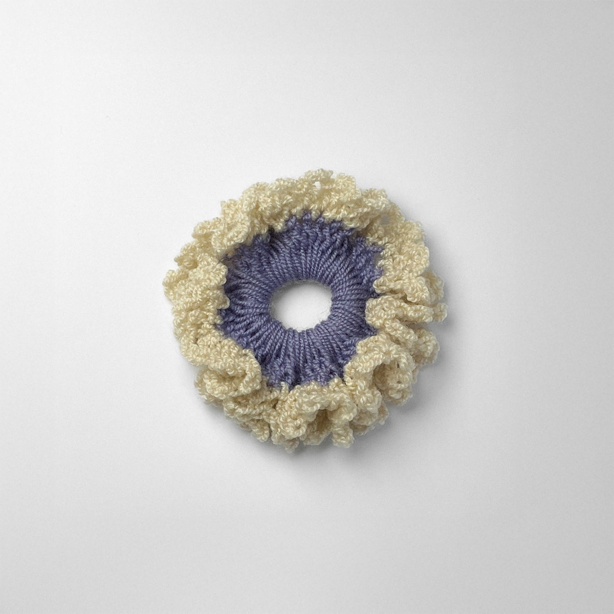 Ręcznie robiona gumka do włosów na szydełku wykonana z materiałów z upcyklingu, widok z góry na białym tle.