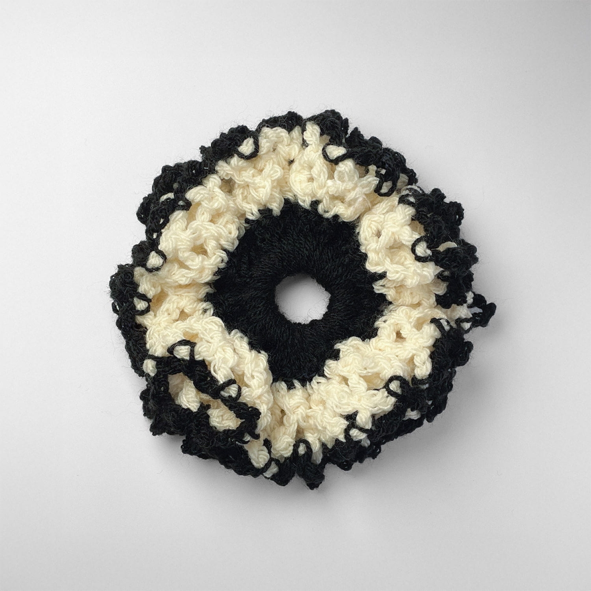 Ręcznie robiona gumka do włosów na szydełku wykonana z materiałów z upcyklingu, widok z góry na białym tle.