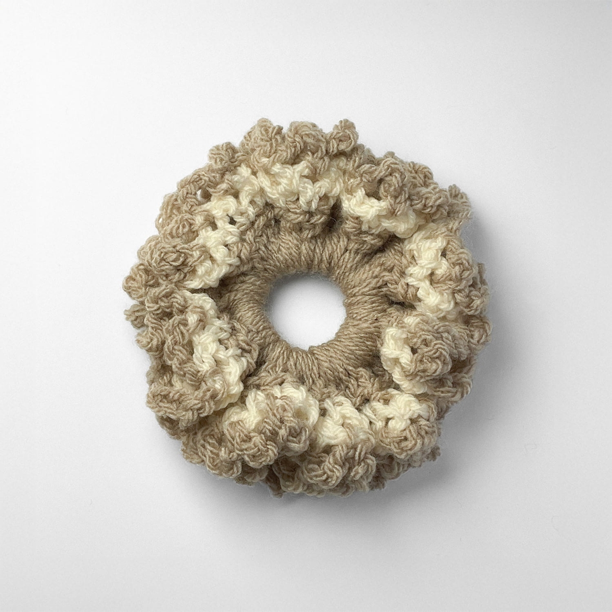 Ręcznie robiona gumka do włosów na szydełku wykonana z materiałów z upcyklingu, widok z góry na białym tle.