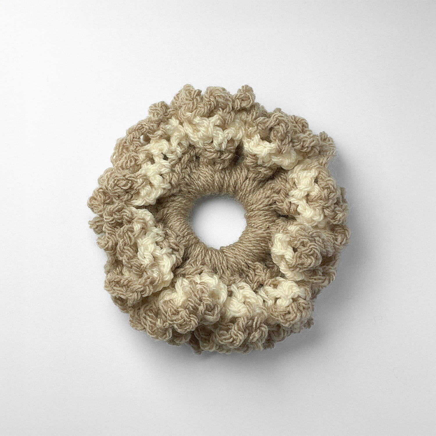 Ręcznie robiona gumka do włosów na szydełku wykonana z materiałów z upcyklingu, widok z góry na białym tle.