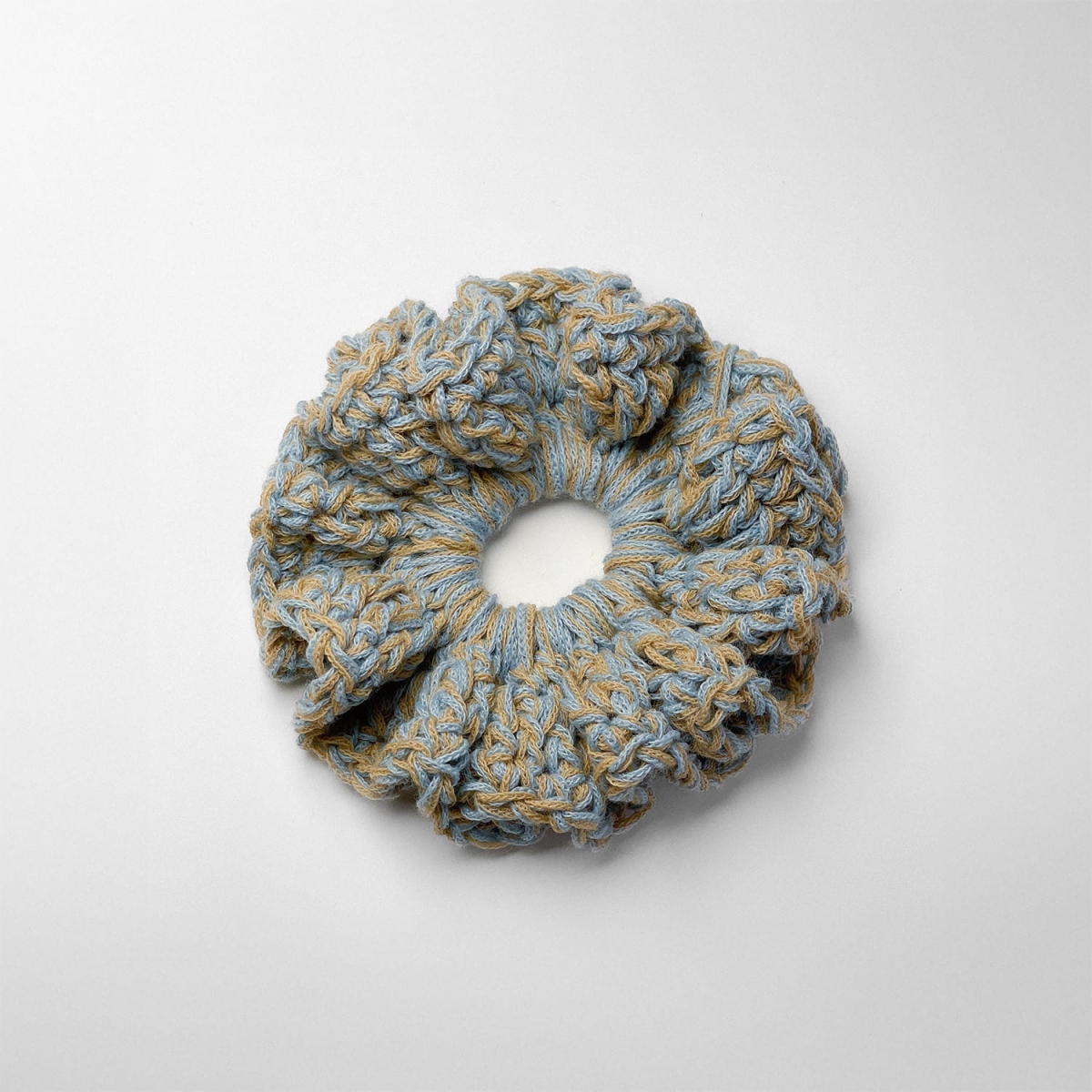 Ręcznie robiona gumka do włosów na szydełku wykonana z materiałów z upcyklingu, widok z góry na białym tle.