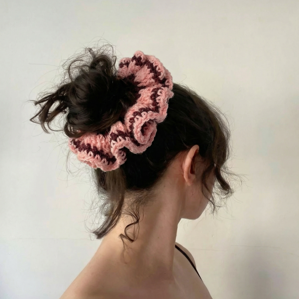 Ręcznie robiona gumka do włosów na szydełku wykonana z materiałów z upcyklingu, pokazana na włosach modelki.