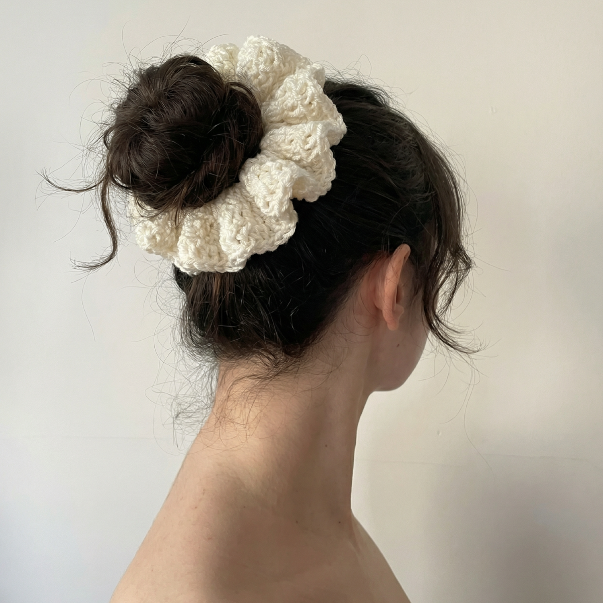 Ręcznie robiona gumka do włosów na szydełku wykonana z materiałów z upcyklingu, pokazana na włosach modelki.