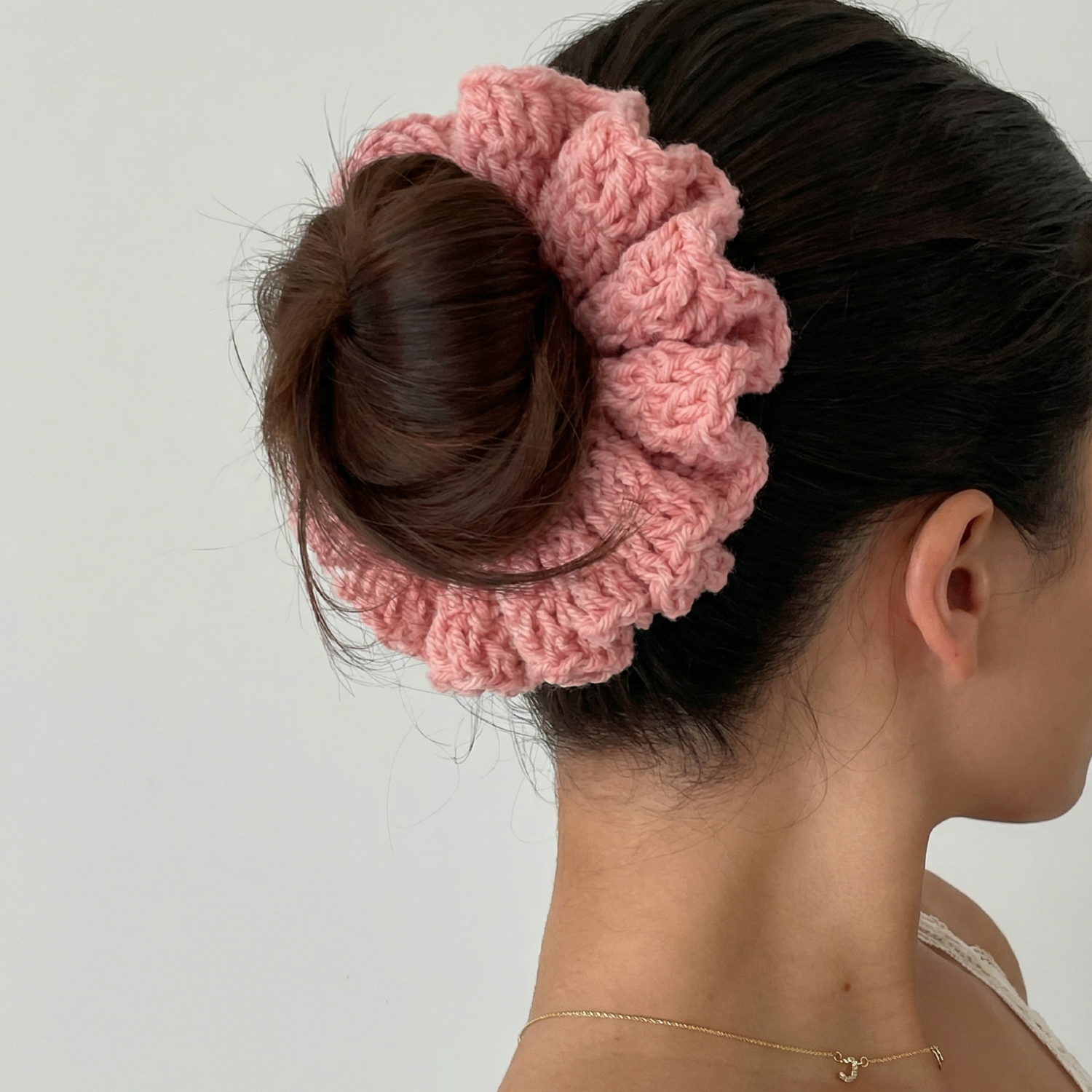 Ręcznie robiona gumka do włosów na szydełku wykonana z materiałów z upcyklingu, pokazana na włosach modelki.