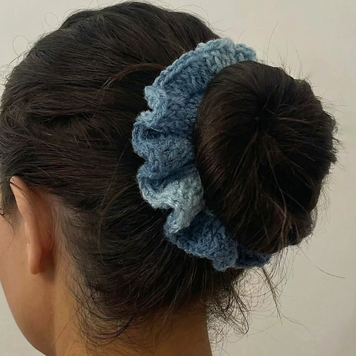 Ręcznie robiona gumka do włosów na szydełku wykonana z materiałów z upcyklingu, pokazana na włosach modelki.