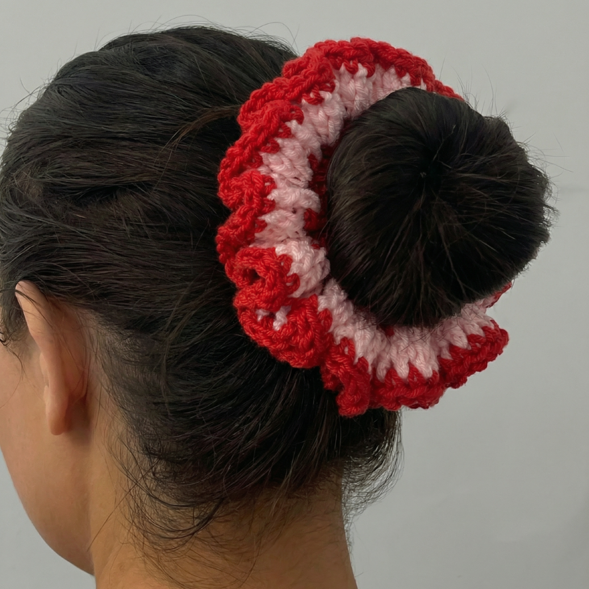 Ręcznie robiona gumka do włosów na szydełku wykonana z materiałów z upcyklingu, pokazana na włosach modelki.