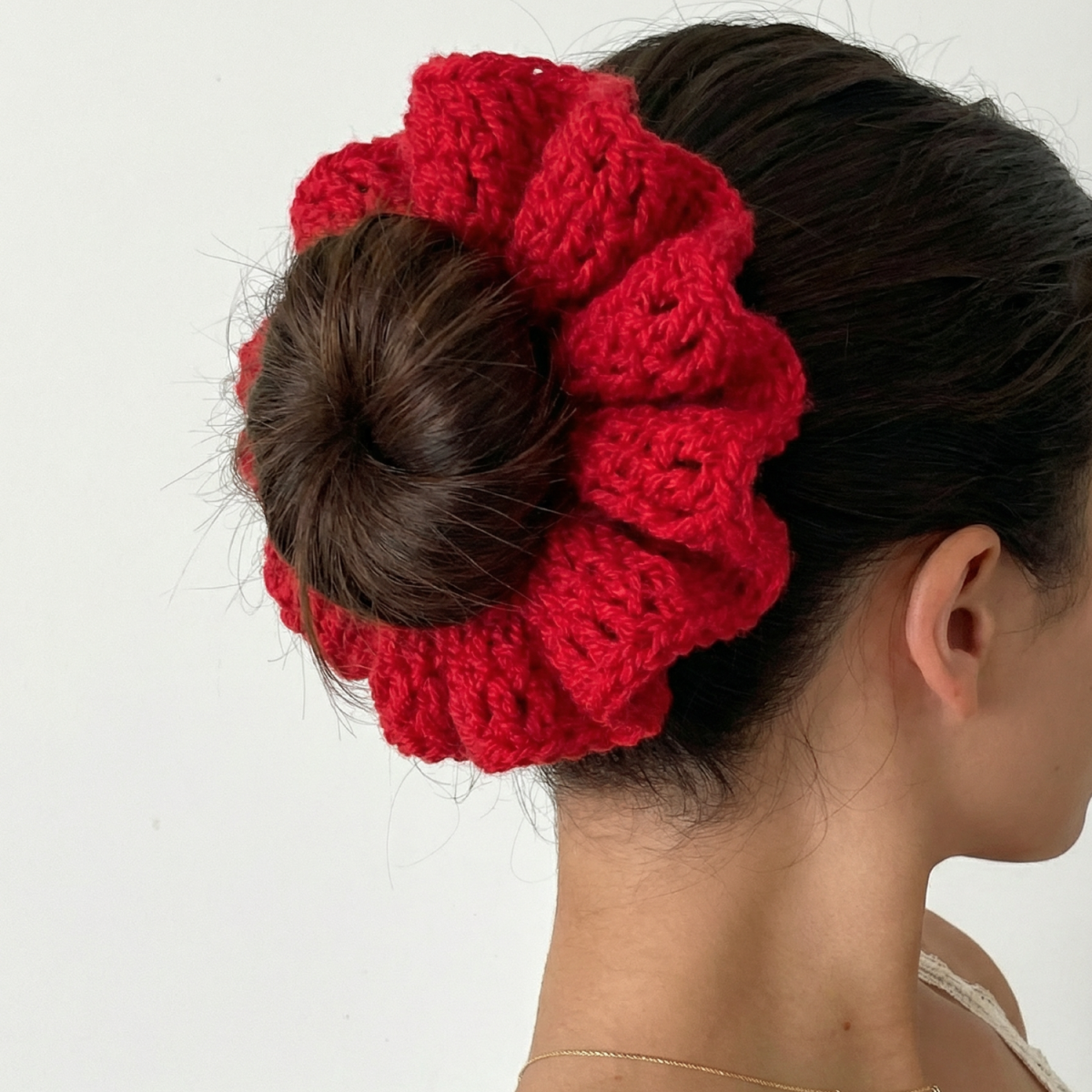 Ręcznie robiona gumka do włosów na szydełku wykonana z materiałów z upcyklingu, pokazana na włosach modelki.
