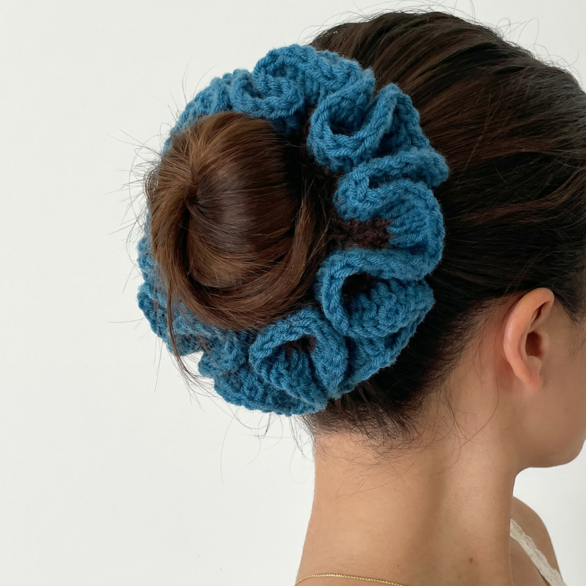 Ręcznie robiona gumka do włosów na szydełku wykonana z materiałów z upcyklingu, pokazana na włosach modelki.