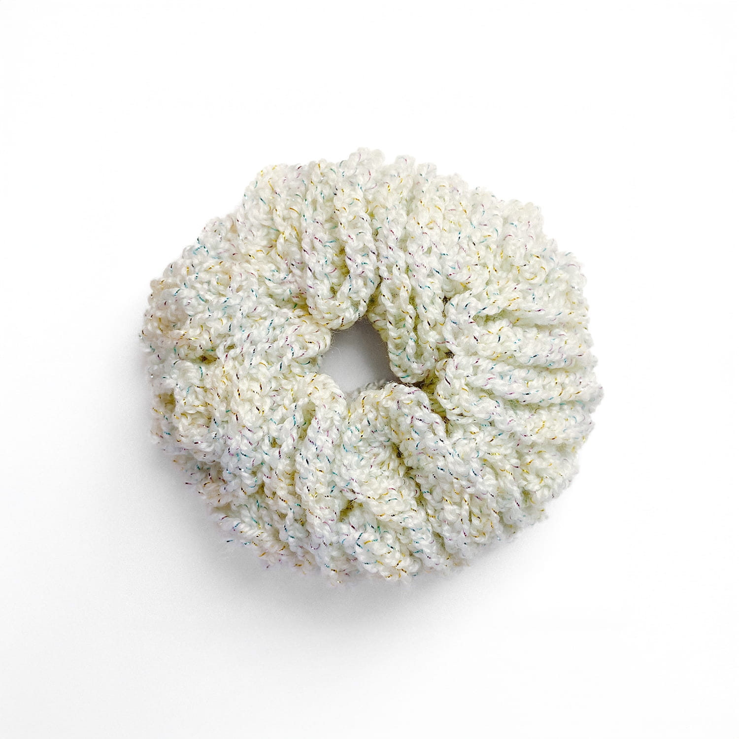 Ręcznie robiona, tęczowa  gumka do włosów na szydełku wykonana z materiałów z upcyklingu, widok z góry na białym tle.