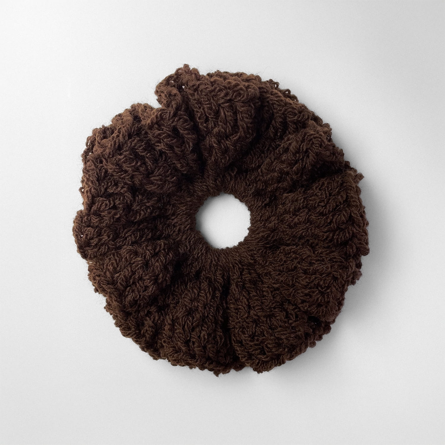 Ręcznie robiona, puchata  gumka do włosów na szydełku wykonana z materiałów z upcyklingu, widok z góry na białym tle.