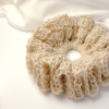Ręcznie robiona, puchata  gumka do włosów na szydełku wykonana z materiałów z upcyklingu, widok z góry na białym tle.