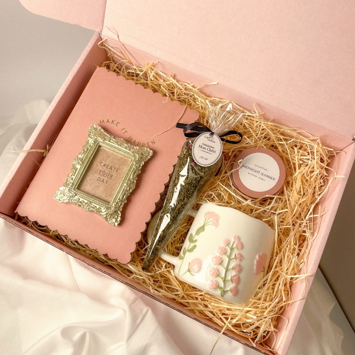 Zestaw prezentowy z różowym notesem, herbatą, świeczką i wiosennym kubkiem.