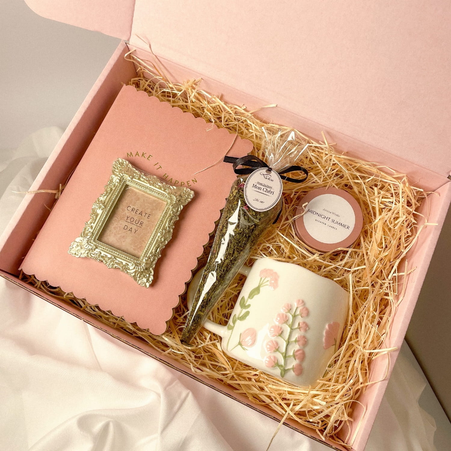 Zestaw prezentowy z różowym notesem, herbatą, świeczką i wiosennym kubkiem.