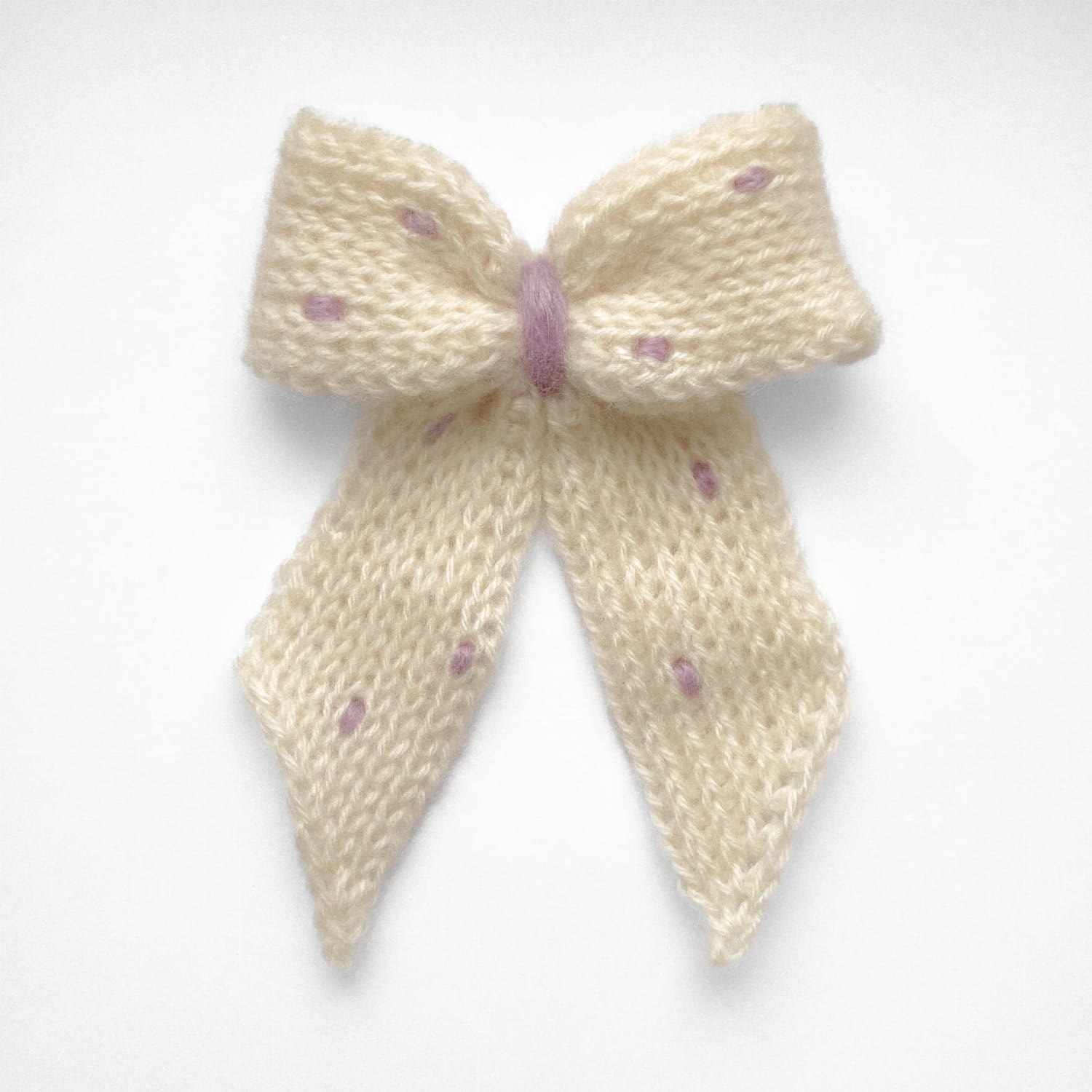 Ręcznie dziergana spinka do włosów w formie kokardy, widok z góry na jasnym tle.