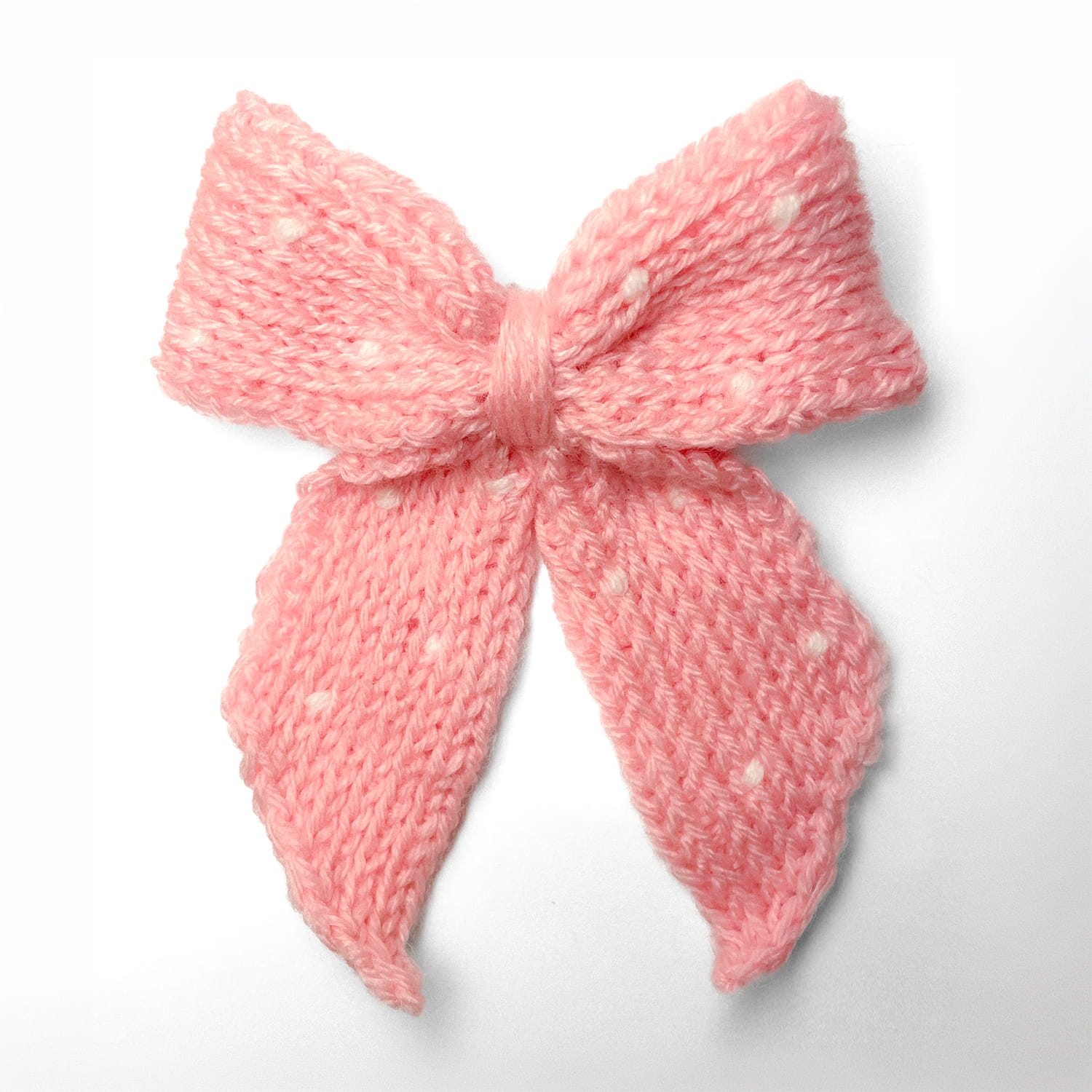 Ręcznie dziergana spinka do włosów w formie kokardy, widok z góry na jasnym tle.