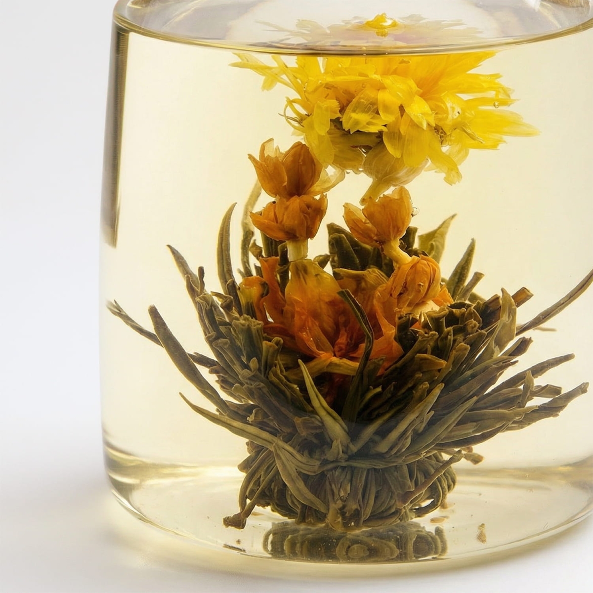 Kwitnąca biała herbata Phoenix Dance rozwijająca się w szklanym dzbanku z widocznym kwiatem goździka i osmantusa